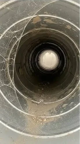 Round metal duct before cleaning, coated in dust