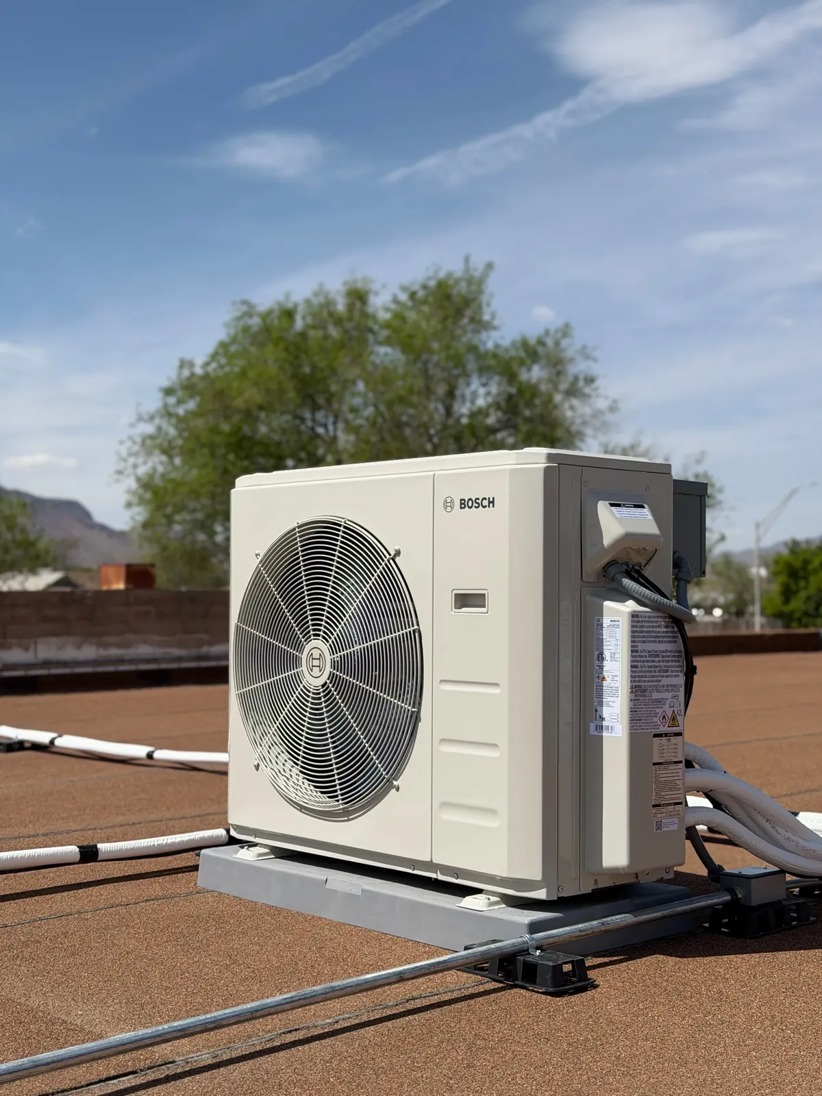 Mini split outdoor unit on a commercial roof under a blue sky