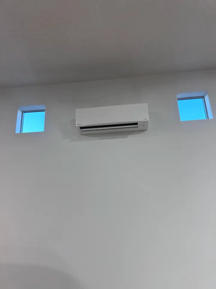 Mini split indoor head between two windows in a bright room