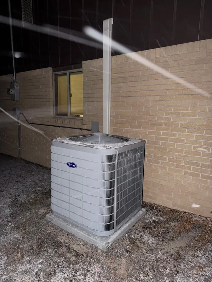 Carrier condenser on a pad beside a brick home