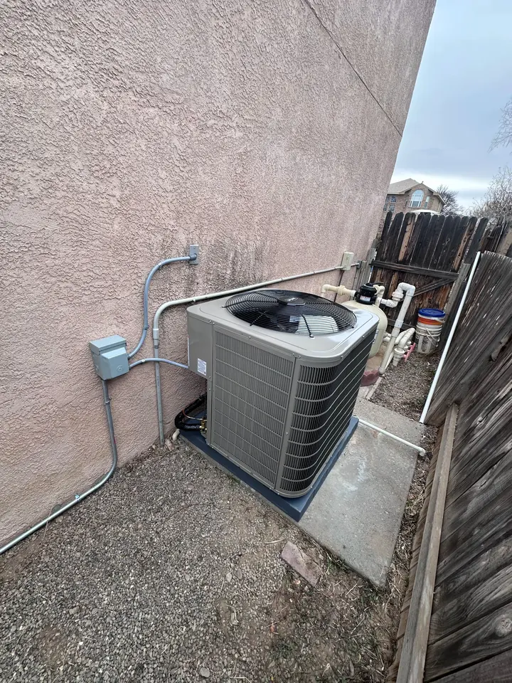 Condenser beside a stucco home next to its disconnect