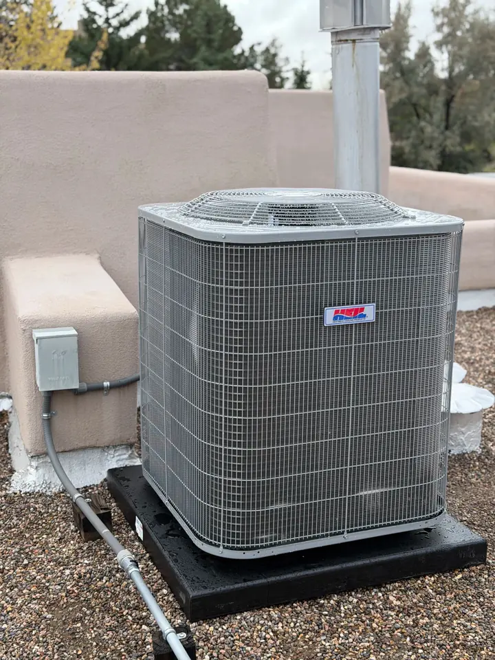 Condenser on a rooftop pad next to a parapet
