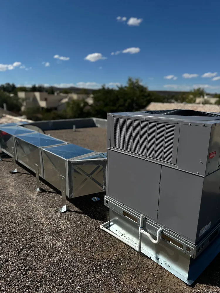 Large rooftop HVAC unit beside a run of metal ductwork